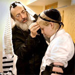 rabbi teaching a bar mitzvah boy how to put on tefillin, teffilin, phylacteries